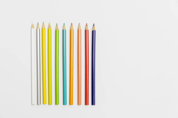 Ten multi-colored pencils in a row on a white background. Place for text