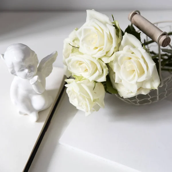 Ένας Λευκός Άγγελος Φαγεντιανής Και Τρία Τριαντάφυλλα Είναι Στο Τραπέζι — Φωτογραφία Αρχείου