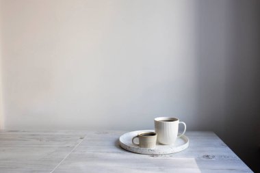 Minimalist İskandinav tarzı. Masadaki tepside iki kişi için farklı boyutlarda iki fincan kahve..