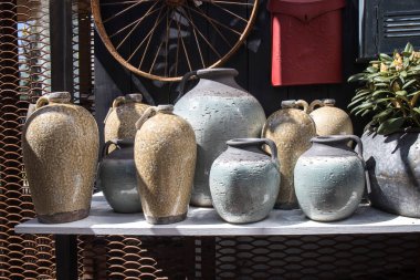 Eski püskü bir duvarda asılı dekoratif posta kutularının arka planına karşı raftaki kil amfora ve çeşitli şekil ve renkte çömlek seçimi