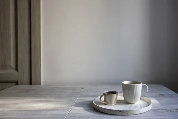 简约的斯堪的纳维亚风格 简约的斯堪的纳维亚风格 在桌上的盘子里放两杯不同大小的咖啡 — 图库照片
