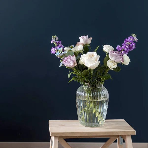 ハケリア ヴェルチナ 紫と白のバラ 小さなお茶のバラ マッティオラ インカーナと黒の背景の反対側のガラスの花瓶に青の虹彩の花束 正方形のフレーム — ストック写真