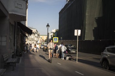 Moskova, Rusya - 21 Haziran 2021, elektrikli scooterlı esmer bir kız Bolshaya Nikitskaya caddesi boyunca bisiklet yolu boyunca geziyor.
