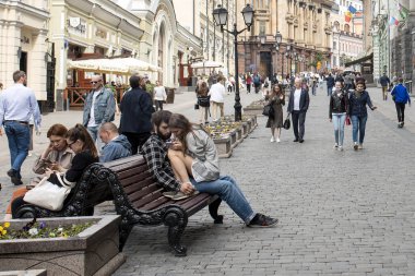 Moskova, Rusya, - 20 Haziran 2021, Kuznetsky Caddesi. İnsanlar yaz havasında bir bankta oturur, alışverişe giderler.