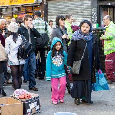 Londra, İngiltere - Kasım 2019, Anne ve kızı Brick Lane 'deki bir pazar bit pazarında giyim standları arasında yürüyor.