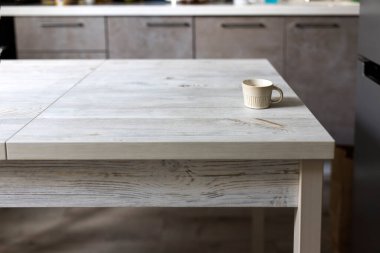 Bej renkli, yuvarlak kahve fincanı bej mutfak iç tarafındaki ahşap masada yer.