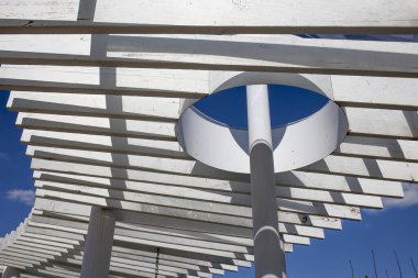 Işık ve gölge kavramı, güneş ışığı duvardaki beyaz ahşap tentenin içinden, soyut arka planda parlar..