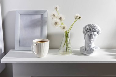 Kimyasal bir şişede bir sürü tüylü karahindiba boş bir fotoğraf çerçevesi, bir fincan espresso kahvesi ve beyaz bir çekmecede David 'in alçı başlığı. Boşluğu kopyala