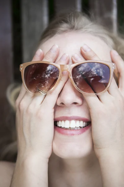 Fröhliches, lachendes Mädchen verdeckte ihr Gesicht mit den Händen und trug eine Sonnenbrille — Stockfoto