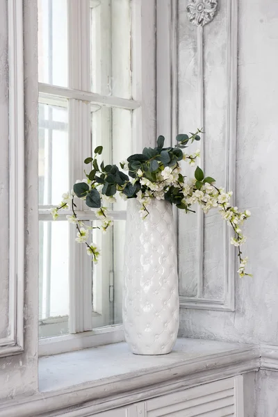 Natura morta con bouquet di fiori di ciliegio artificiali in un vaso cinese sul davanzale della finestra in interni bianchi — Foto Stock