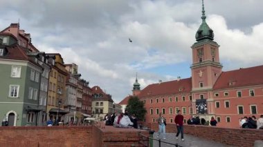 Varşova, Polonya, 8 Ekim 2025. Castle Meydanı, Kraliyet Kalesi 'nin antik savunma duvarının yanında yükseldiği Eski Şehir' in girişini gösteriyor. Gökyüzü bulutlarla ve güneş ışığıyla dolu..