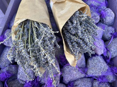 Mor keselerden bir yatakta iki buket kurutulmuş lavanta.