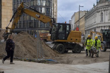 Varşova, Polonya, 12 Ekim 2025, kazıcı, işçi ve modern ve tarihi binaları olan bir şehir merkezinde inşaat alanı