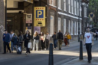 Londra, İngiltere, 2 Mayıs 2025. Shoreditch Londra 'da güneşli bir şehir sokağında yürüyen bir kalabalık.