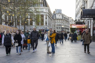 Londra, İngiltere, 2 Mayıs 2025. Bir grup yaya, merkezde kucaklaşan bir çift, geleneksel ve modern mimari ile çevrili Leicester Meydanı 'nda yürüyor,' Casino 'tabelası olan bir bina da dahil..