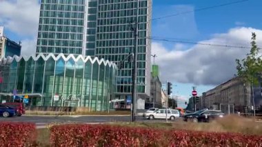 Varşova, Polonya, 2 Ağustos 2025, benzersiz bir zig-zag tabanlı modern cam gökdelen işlek bir caddenin üzerindeki parlak mavi gökyüzünü ve beyaz bulutları yansıtır. Widok Kuleleri bir ofis gökdelenidir.