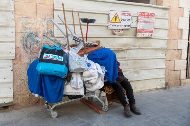 Kudüs, İsrail, 23 Ekim 2025, plastik sandalyeler, çantalar ve süpürge de dahil olmak üzere kişisel eşyalarla dolu geçici bir tramvay şehrin kaldırımında bir inşaat çitinin yanında duruyor..