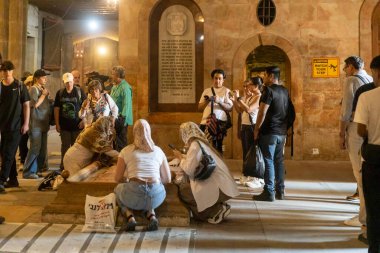 Kudüs, İsrail, 23 Ekim 2025, hacılar ve turistler kutsal mezarlık kilisesinin içindeki yağ taşının etrafında toplandılar, bazıları da taşa dokunmak ya da öpmek için diz çöktü..