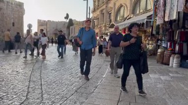 Kudüs, İsrail, 23 Ekim 2025, İnsanlar Jaffa Kapısı 'ndan Eski Şehir' in önünden geçerek gün batımının altın ışığında hediyelik eşya dükkanlarına doğru yürüyorlar..