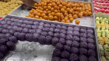 Kamera, baklava, Türk lokumu, halva ve kadaifi de dahil olmak üzere geleneksel Türk tatlılarını gösteren bir pazar tezgahı boyunca hareket ediyor..