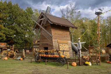 Varşova, Polonya, 2 Ekim 2025, Tom Amca 'nın Çiftliği. Sonbahar için tasarlanmış tuhaf, ahşap bir yel değirmeni yapısı. Balkabakları ve ahşap bir duvarda gerçek boyutta bir korkuluk..
