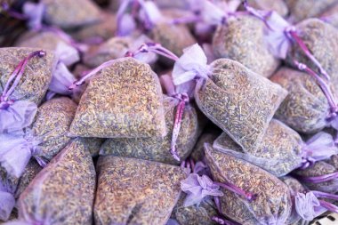 Kurumuş lavanta tomurcuklarıyla dolu, çok sayıda küçük, saf lavanta renkli organza torbalarının yakın çekimi, yığınla satılmaya hazır..