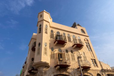 Tel Aviv, İsrail, 6 Ekim 2025, Eski Jaffa 'nın Shuk Hapishpeshim ilçesinde Hanina Ben Dosa Caddesi ve Yehuda Margoza Caddesi' nin köşesindeki kemerli camlı ve demirden balkonlu Eklektik tarzı bina.