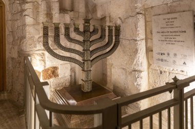 Kudüs, İsrail, 9 Ekim 2025, Kral David 'in Zion Dağı' ndaki mezarında büyük, karmaşık bir şekilde dekore edilmiş bronz bir menora sergilendi, antik taş duvarlara karşı dizildi ve metal bir korkulukla korundu..
