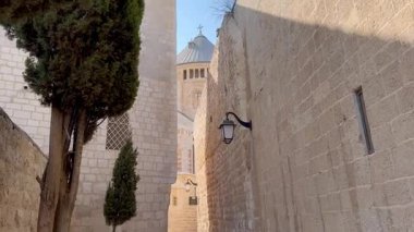 Kudüs, İsrail, 9 Ekim 2025 etkileyici Dormition Abbey Zion Dağı 'nın tepesinde klasik fenerler ve kaldırım taşı sokağıyla çevrili dar bir şehir sokağında görüldü..