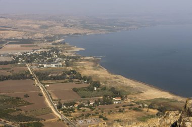 Tiberias, İsrail: Arbel Doğa Koruma Alanı ve Ulusal Park 'tan panoramik yüksek açı manzarası aşağıdaki tarlalar, yollar ve tatil beldeleri ile Celile Denizi kıyılarını gösteriyor.