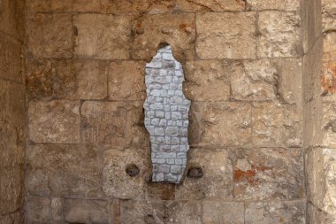 Benzersiz, dikey, düzensiz bir deliğe sahip eski bir taş duvarın dokulu yakın çekimi daha küçük ve pürüzlü taşların iç katmanını ortaya çıkarıyor..