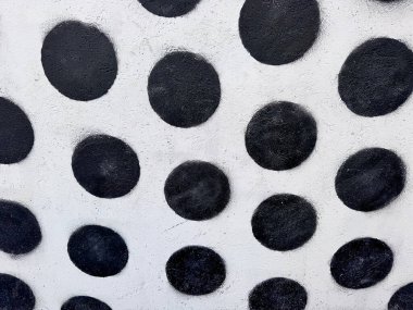 Kabataslak beyaz arka planda geniş siyah benekli düzensiz bir desenle boyanmış bir duvarın soyut yakın çekimi..