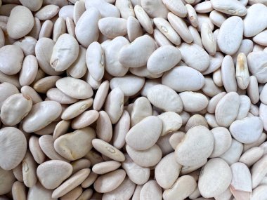 Pişmemiş, pürüzsüz, beyaz fasulye (ya da tereyağlı fasulye) yığınının detaylı, tam çerçeve çekimi, dokularını ve doğal şekillerini gözler önüne serer..