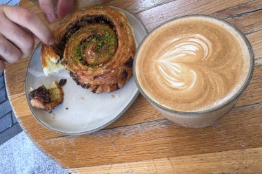 Ellerinizi kapayın, tarçınlı ve şam fıstıklı pastayı büyük bir fincan sütlü sanat kahvesiyle paylaşın.