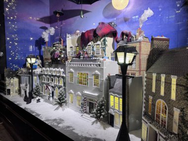 Londra, İngiltere, 7 Aralık 2025, Selfridges Noel penceresi, Mary Poppins 'ten esinlenilmiş minyatür bir kar kaplı Londra caddesini gösteriyor, şenlikli ağaçlar, yanan lambalar, yüzen kırmızı bir eşarp ve şemsiye.