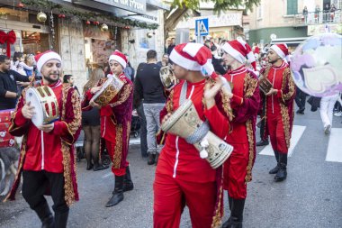 Hayfa, İsrail, 20 Aralık 2025, Noel Keşif Alayı, geleneksel kırmızı kostümlü müzisyenler bateri ve tef çalıyor..