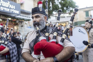 Hayfa, İsrail, 20 Aralık 2025, Noel keşif geçidi, geleneksel üniformalı sakallı bir adam gayda çalıyor..