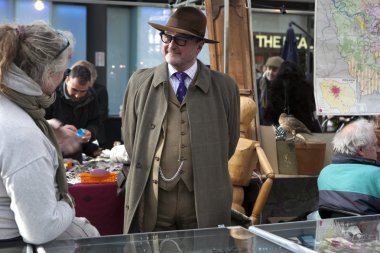 iyi giyimli satıcı şapka alışveriş ile konuşuyor. Bit pazarı eski moda ürünler Londra şehir içinde görüntülenen ile,