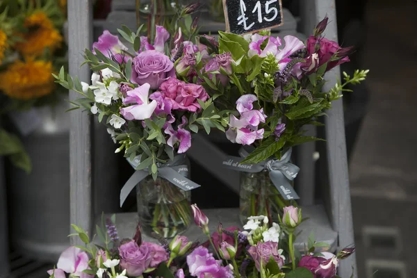 Bouquet aus Erbsen, Lathyrus odoratus, Blüten in einer violetten Vase auf hölzernen, grauen Stufen — Stockfoto