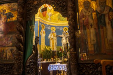 Nasıra, İsrail, 24 Aralık 2025, Yunan Ortodoks Kilisesi. Duvar resimleri ve ikonları olan bir ortodoks kilisesinin mihrabına oyulmuş ahşap bir ikonostaz ile bakın..