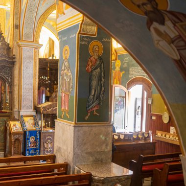 Nasıra, İsrail, 24 Aralık 2025, bir Yunan Ortodoks Annunciation Kilisesi 'nin içi. Sütunlar ve kemerli duvarlar, ahşap sıralar üzerine azizlerin resmedilmiş simgeleri..