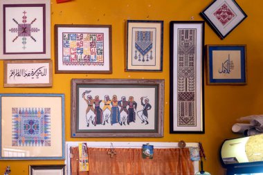 Nasıra, İsrail, 24 Aralık 2025, Nasıra 'da çerçevelenmiş geleneksel Filistin nakışı ve çapraz dikişli sanat eserleriyle süslenmiş sarı bir duvar.