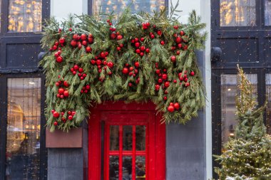Parlak kırmızı restoran kapısı yemyeşil çelenkler ve kışın kırmızı Noel mücevherleri ile süslenmiş, Moskova, Rusya
