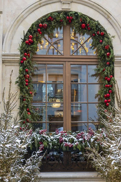 Önünde kırmızı mücevherler ve karlı çalılar olan Noel çelengi çerçeveli geniş kemerli pencere, Moskova, Rusya
