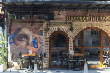 İstanbul, Türkiye, 5 Mayıs 2025, tuğla kemerler, boş masalar ve sandalyeler ile dış cephe cephesi ve duvarda büyük bir göz resmi,