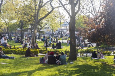 İstanbul, Türkiye, 5 Mayıs 2025, İstanbul, Uskudar 'daki ağaçlar ve banklarla güneşli çimlerde piknik yapan ve dinlenen farklı aileler