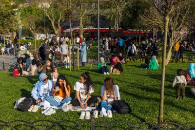 İstanbul, Türkiye, 5 Mayıs 2025 Çit ve ağaçların yakınındaki çimlerde piknik yapan karışık gruplar, İstanbul parkında dinlenen genç yetişkinler, Uskudar
