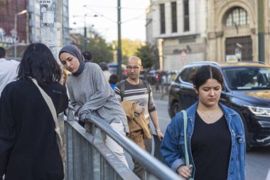 İstanbul, Türkiye, 5 Mayıs 2025, türbanlı genç kadınlar cadde yakınlarındaki metal korkuluklara yaslanıyor ve Pilsan Elektronik sho