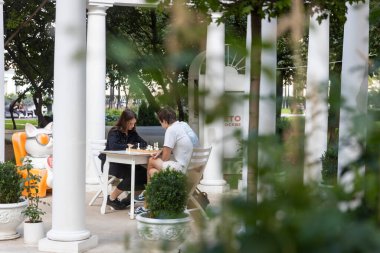 Moskova, Rusya, 17 Temmuz 2025 Moskova 'da beyaz sütunlu beyaz bir pavyonda iki kişi satranç oynuyor.