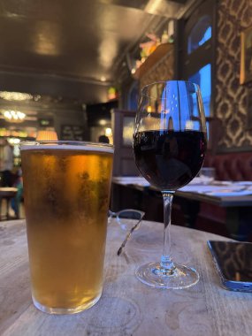 Bira birası ve kırmızı şarapla dolu şarap bardağı. Lokanta içlerindeki kırmızı şarap masasında. Arka planda bulanıklık var.